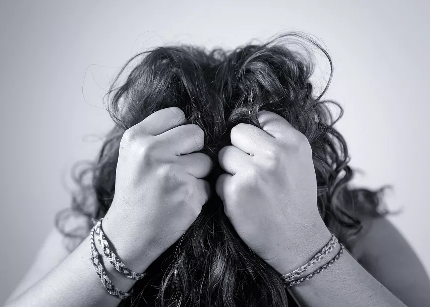 Verzweifelte Frau fasst sich bei gesenktem Kopf an die Haare Verzweifelte Frau fasst sich bei gesenktem Kopf an die Haare